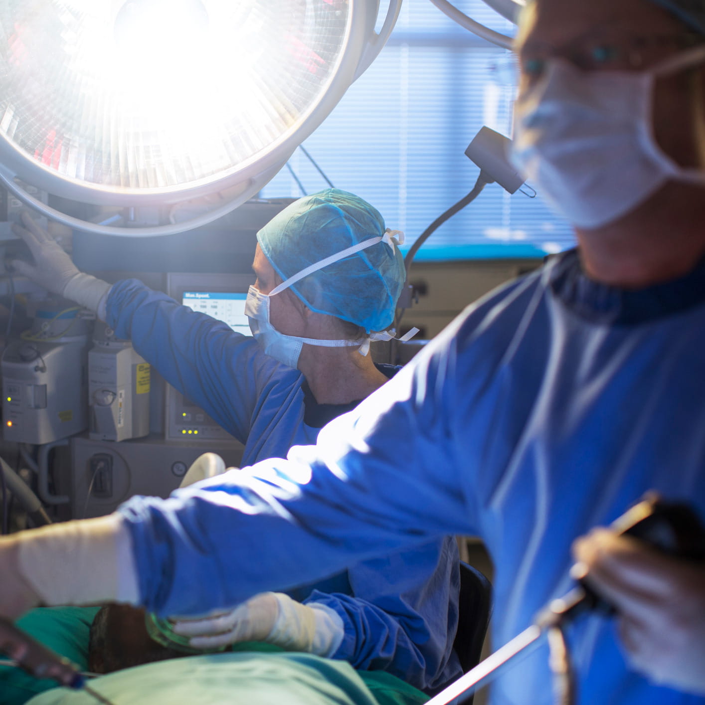 Een gespecialiseerd operatieteam voert een complexe neurochirurgische ingreep uit onder een krachtige operatielamp. Met uiterste precisie bedienen de chirurgen de microscopische instrumenten en bewakingsapparatuur.